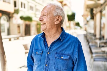 Senior man with grey hair standing happy outdoors on a sunny day. Smiling happy at 70s for...