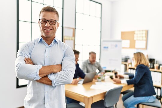 Middle age caucasian businessman smiling happy standing with arms crossed gesture at the office during business meeting.