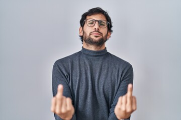 Handsome latin man standing over isolated background showing middle finger doing fuck you bad...