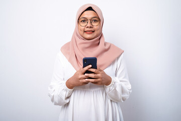 Young asian muslim woman smiling using mobile phone