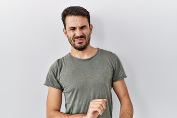 Young hispanic man with beard wearing casual t shirt over white background disgusted expression,...