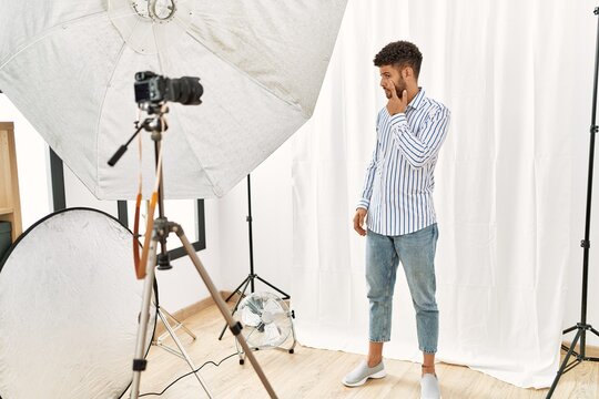 Arab young man posing as model at photography studio pointing to the eye watching you gesture, suspicious expression