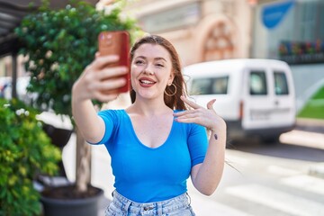 Young redhead woman smiling confident having video call at street
