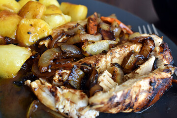 Honey roasted chicken with oven roasted potatoes with gravy sauce on a plate.  Selective focus.  Copy space is on the blurry part of photo. 
