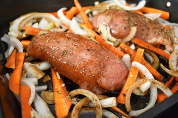 Honey roasted chicken preparation with raw chicken breasts and vegetables in oven tray.