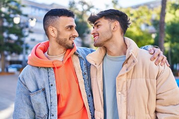 Two man couple hugging each other standing at park