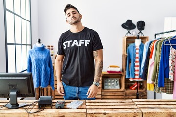 Young hispanic man working at retail boutique looking sleepy and tired, exhausted for fatigue and...