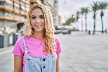 Young blonde woman smiling confident at street