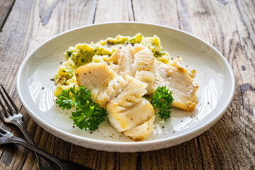 Fish dish - fried cod fillet with potato puree on wooden table
