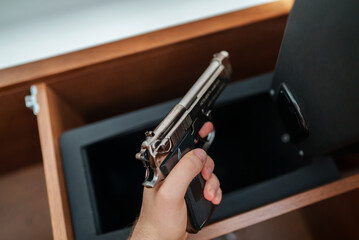 Man takes the weapon from the safe.