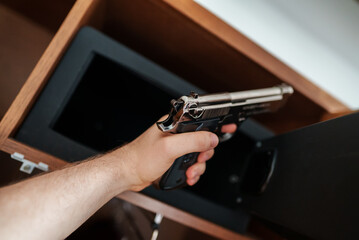 Man takes the weapon from the safe.