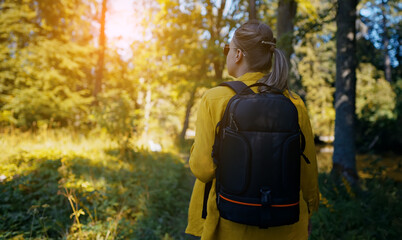 Fototapeta na wymiar Woman tourist with backpack exploring forest. Back view.