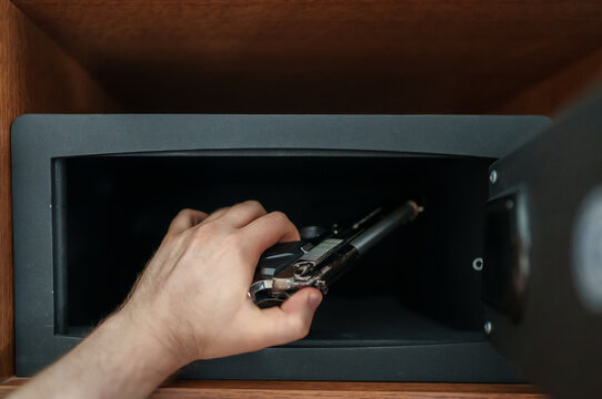 Man puts the weapon in the safe.