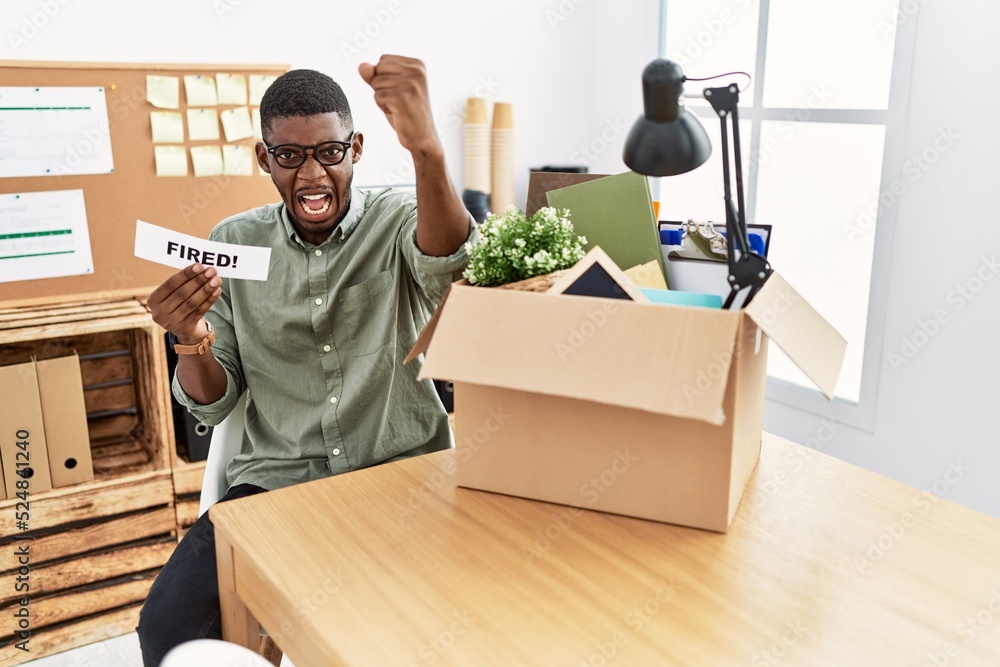 Poster Young african american businessman holding fired banner at the office annoyed and frustrated shouting with anger, yelling crazy with anger and hand raised