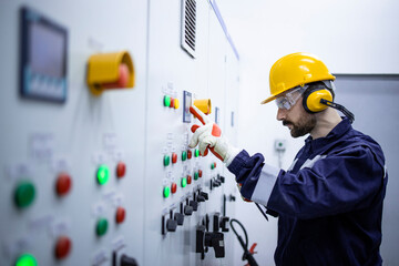Professional electrician standing by electrical cabinet and checking installations and voltage.