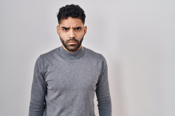 Hispanic man with beard standing over white background skeptic and nervous, frowning upset because of problem. negative person.