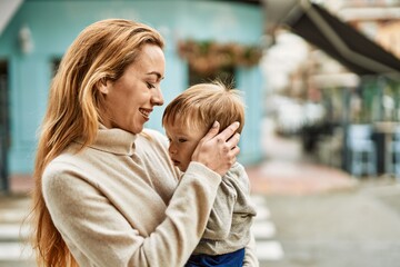 Fototapeta premium Beautiful family of mother and baby son hugging and bonding together with love. Parent and toddler outdoors