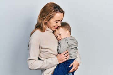 Young caucasian woman holding and hugging her son with love. Family of two bonding together. Mother holding infant toddler