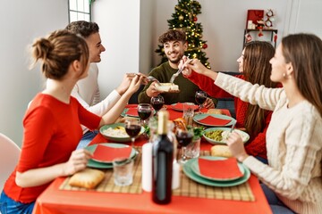 Group of young people smiling happy having christmas dinner at home.