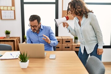 Middle age businesswoman angry with employee. Screaming using megaphone at the office.