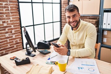 Young hispanic man ecommerce business worker using smartphone at office