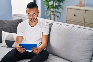 African american man using touchpad sitting on sofa at home