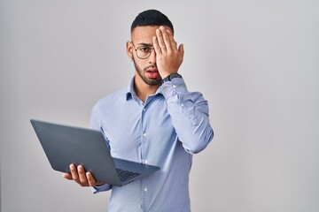 Young hispanic man working using computer laptop yawning tired covering half face, eye and mouth with hand. face hurts in pain.