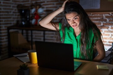 Young teenager girl working at the office at night confuse and wonder about question. uncertain with doubt, thinking with hand on head. pensive concept.
