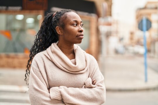 African american woman with relaxed expression and arms crossed gesture at street
