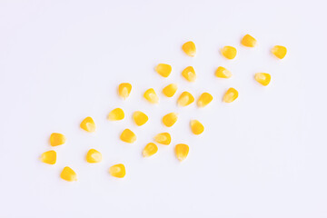 Yellow corn seeds scattered on pink background, Top view