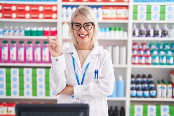 Young caucasian woman working at pharmacy drugstore smiling with happy face winking at the camera...