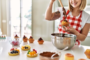 Young caucasian girl smiling happy cooking pumpkins at the kitchen.