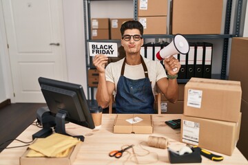 Young hispanic man holding black friday banner small commerce looking at the camera blowing a kiss being lovely and sexy. love expression.