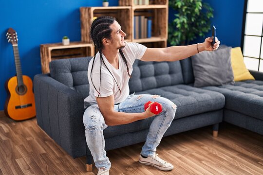 Young man training with dumbbell make selfie by smartphone at home