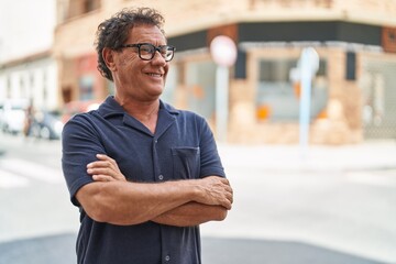 Middle age man smiling confident standing with arms crossed gesture at street