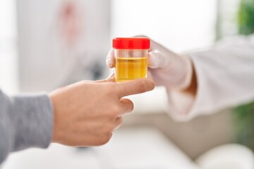 Young man wearing doctor uniform holding analysis test tube at clinic