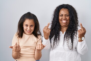 Mother and young daughter standing over white background showing middle finger doing fuck you bad...