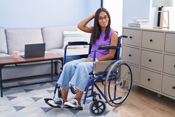 Young hispanic woman sitting on wheelchair at home confuse and wonder about question. uncertain...