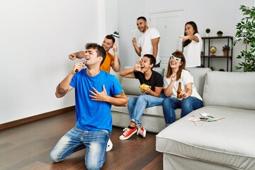 Fototapeta premium Group of young friends having party singing song using microphone at home.