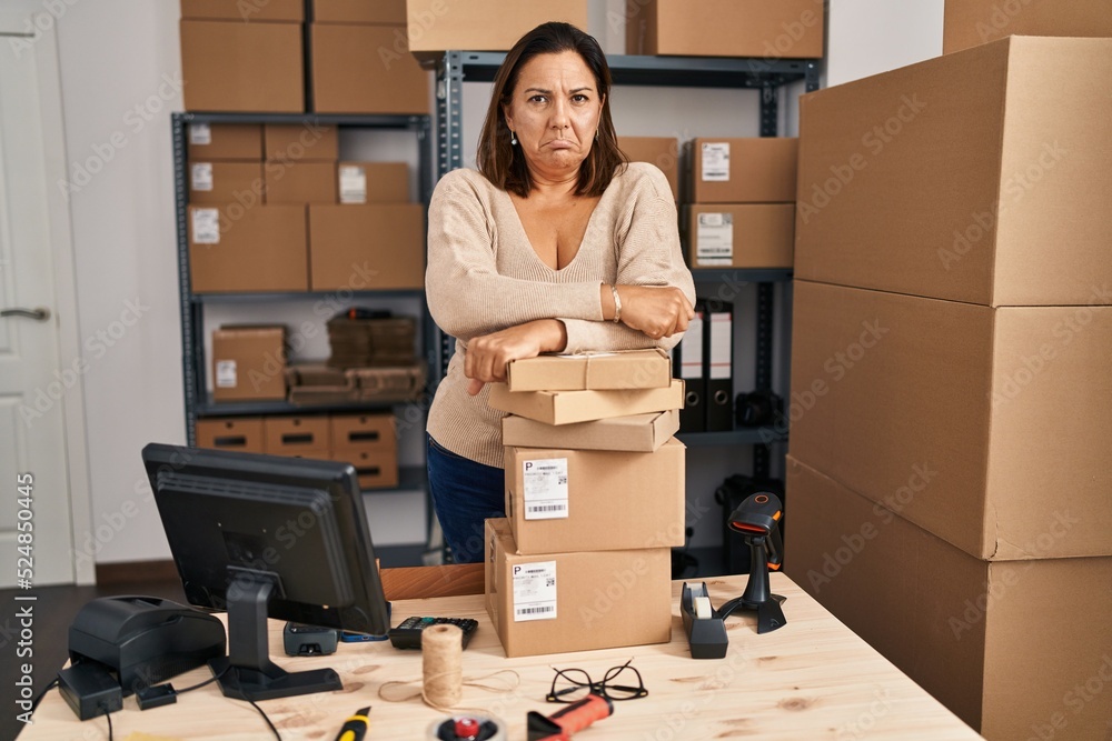 Poster Middle age hispanic woman working at small business ecommerce depressed and worry for distress, crying angry and afraid. sad expression.