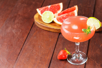 Fresh grapefruit juice in a glass with grapefruit pieces, lime and mint on a wooden background. copy space