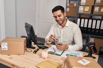 Young hispanic man e-commerce business worker counting dollars at office