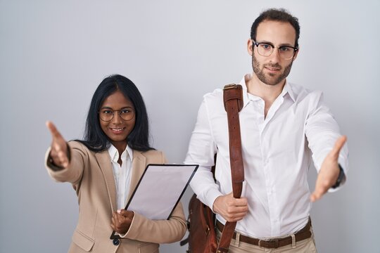 Interracial business couple wearing glasses smiling friendly offering handshake as greeting and welcoming. successful business.