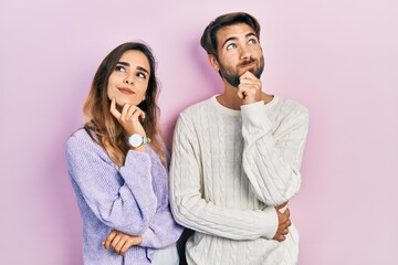 Young hispanic couple wearing casual clothes with hand on chin thinking about question, pensive...