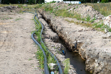 Plastic water pipe lying along the ditch with high groundwater, water connection in the housing...