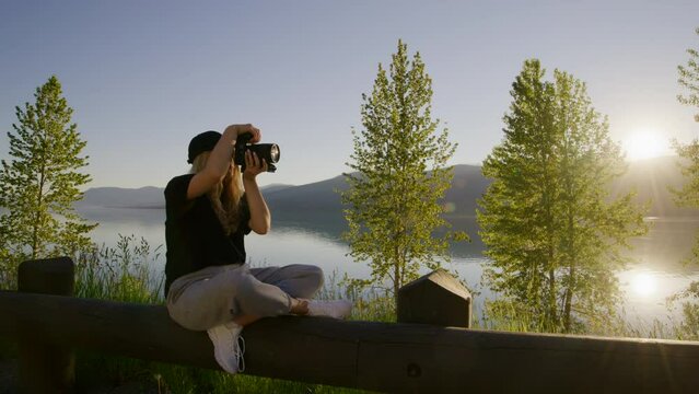 Woman at observation deck during a golden hour picturesque lighting. Female photographer takes pictures of pristine wilderness. High quality 4k footage