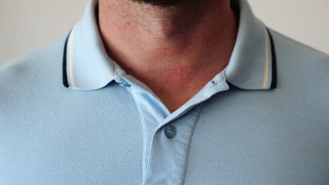 Hands buttoning a polo shirt not completely. Close-up of how to button the collar of a colored polo. Man adjusting his poloshirt collar undoing top button. Feeling relaxed and formal outfit.