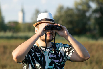 Obraz premium The young birdwacher with binocular obseving bird migration on the field