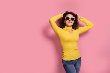 Beautiful young curly caucasian girl in a yellow outfit , who is smiling and posing on pink background 