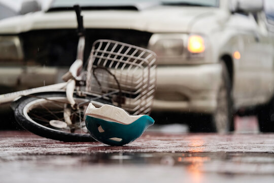 Blurred image of a traffic accident, helmet and bicycle after a car crashes into a cyclist on the road during heavy rain, spot focus.